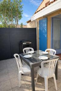 a black table and white chairs on a patio at Mazet avec piscine collective in Le Lavandou