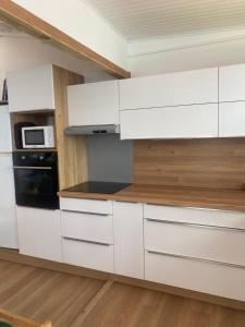 a kitchen with white cabinets and a microwave at La Sucrière in Terre-de-Haut