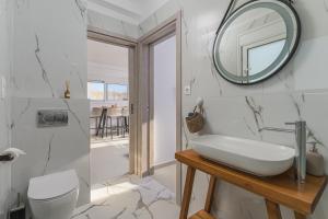 a white bathroom with a sink and a mirror at Azura creta in Gra Liyiá +17 photos