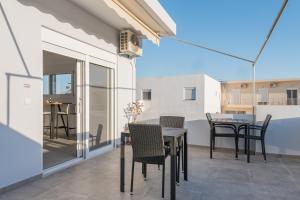 a patio with tables and chairs on a balcony at Azura creta in Gra Liyiá