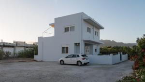 a white house with a car parked in front of it at Azura creta in Gra Liyiá