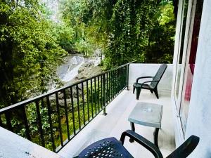 ein Balkon mit zwei Stühlen und Blick auf einen Fluss in der Unterkunft Ranmudu Hotel in Hanwella
