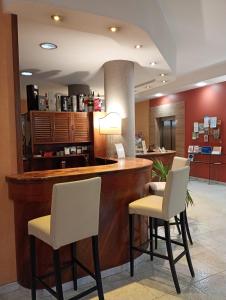 a hotel lobby with a bar with white chairs at Hotel Des Alpes in Rosta