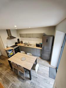 a kitchen with a wooden table and a refrigerator at Duplex climatisé in Aramits +6 photos