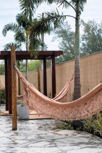 a hammock in a patio with a table and palm trees at Prainha Sand Beach Arraial do Cabo in Arraial do Cabo