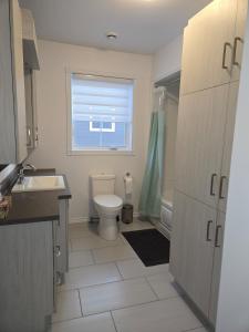 a bathroom with a toilet and a sink and a window at Appartement de 2 chambre à la baie in Saguenay