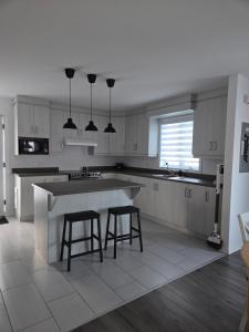 a kitchen with a large island with two bar stools at Appartement de 2 chambre à la baie in Saguenay
