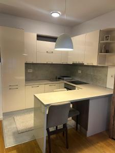 a kitchen with white cabinets and a table and a chair at Skyline Residence Podgorica in Podgorica