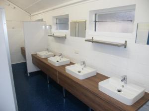a bathroom with two sinks and two mirrors at Mietwohnwagen E2 am Flussufer in Wienhausen +2 photos