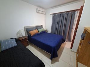 a bedroom with a blue bed and a window at Departamentos Roxy in Viedma