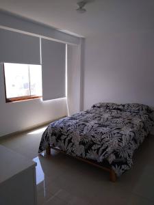 a bedroom with a bed in a white room with a window at Surfers Paradise - Casa Caro in Punta Negra