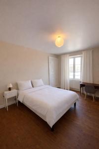 a bedroom with a large white bed and a window at Les volets verts in Pont-Croix
