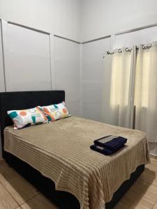 a bedroom with a bed with a blanket and pillows at Chácara pontarolo in Guarapuava