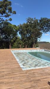 a swimming pool with a wooden floor and a wooden deck at Chácara pontarolo in Guarapuava