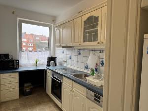 a kitchen with white cabinets and a sink and a window at Vina Ferienwohnung in Emden +8 photos