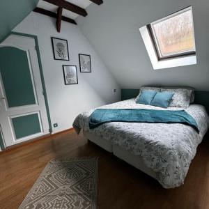 a bedroom with a bed with blue pillows and a window at L écrin de l aube in Grainville-la-Teinturière