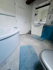 a bathroom with a white tub and a blue rug at L écrin de l aube in Grainville-la-Teinturière