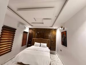 a bedroom with a white bed and a wooden headboard at De Rex Luxury Apartment in Akwa
