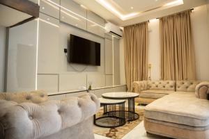 a living room with a couch and a tv at De Rex Luxury Apartment in Akwa