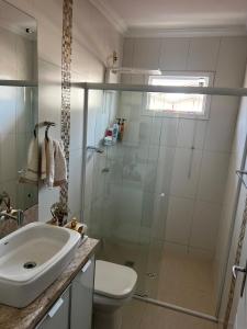 a bathroom with a shower and a sink and a toilet at Casa com churrasqueira e ar para até 8 pessoas in Guabiruba +22 photos
