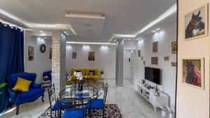 a living room with a glass table and blue chairs at Casa Pyramids View in Cairo