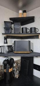 a kitchen counter with shelves with pans and utensils at The Orchard's Nook Treehouse in Cottenham