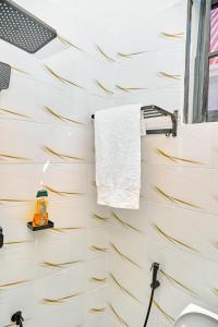 a bathroom with white tiles and a towel on a wall at Ngao Apartment and Suites Dodoma in Dodoma +65 photos