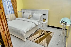 a bedroom with a white bed and a chair at Ngao Apartment and Suites Dodoma in Dodoma