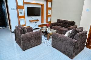 a living room with two chairs and a flat screen tv at Ngao Apartment and Suites Dodoma in Dodoma