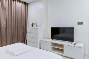 a white bedroom with a bed and a tv at Sunrise Stay in Male City