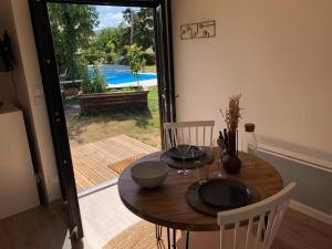 a wooden table with chairs and a table and a pool at Tiny House le Cocon de Jardin in Saverne