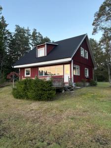 a red house with a black roof at Åker Lilläng Strandstugan in Åker