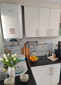 a kitchen with white cabinets and a vase of flowers on a counter at Loft con encanto de Raúl y Rosa in San Sebastián de los Reyes