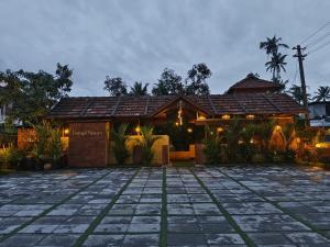 a house with a tile roof and a stone patio at Ponyo Stays in Cochin