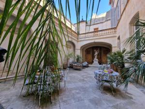 a courtyard with tables and chairs in a building at Palais de Luppé, Chambre d'hôtes in Arles