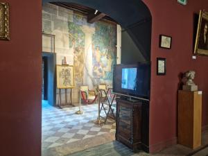 a living room with a tv and a painting on the wall at Palais de Luppé, Chambre d'hôtes in Arles