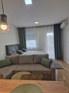a living room with a couch and a bed at Muki Oaza Apartman in Tuzla