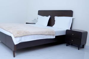 a bed with white sheets and pillows and a night stand at Zubi Guest House in Dargai