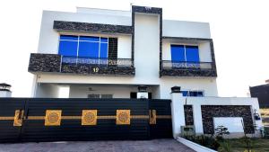 a black fence in front of a white house at Zubi Guest House in Dargai