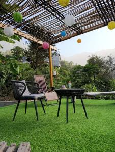 a patio with two chairs and a table on grass at Tiny House Ribeira Principal in Mato Correia