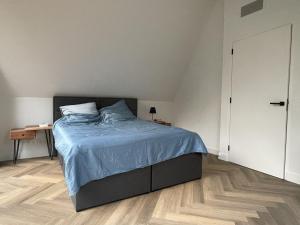 a bedroom with a bed with a blue comforter at Villa Hogerop in Bennekom