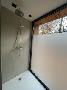 a shower in a bathroom with a window at Villa Hogerop in Bennekom
