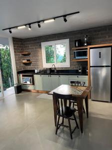 a kitchen with a table and a stainless steel refrigerator at Refúgio das Araucárias in Nova Petrópolis