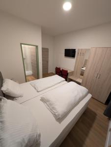 a bedroom with two white beds and a television at Hotel Shiva in Maingründel +7 photos