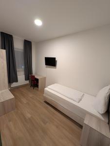 a bedroom with a bed and a desk and a television at Hotel Shiva in Maingründel