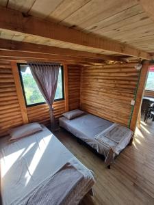 two beds in a room with wooden walls at Cabañas Buenos aires in Guadalupe