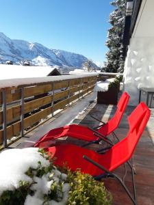 zwei rote Stühle auf einem Deck im Schnee in der Unterkunft Ferienwohnung & Spa Renate in Sibratsgfäll