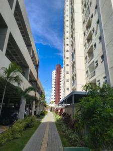 a walkway between two tall buildings with palm trees at Apartamento Cabedelo João Pessoa in Cabedelo