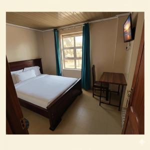 a bedroom with a bed and a table and a window at Crown Accommodation Narok in Narok