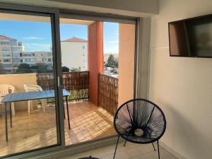 a room with a balcony with a table and a fan at appartement vue mer in Frontignan +2 photos